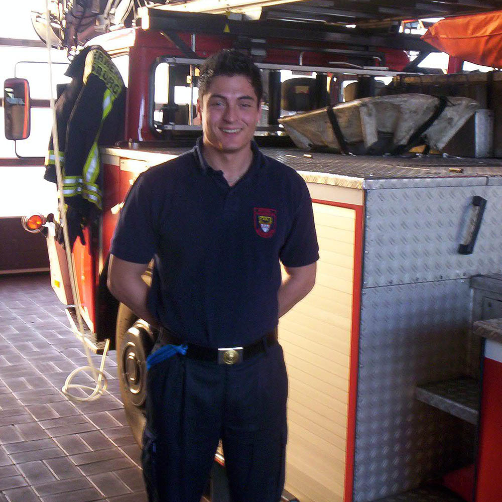 Enrico ist Gründer von fireandfight und steht als Feuerwehrmann vor der Drehleiter seiner Feuerwache